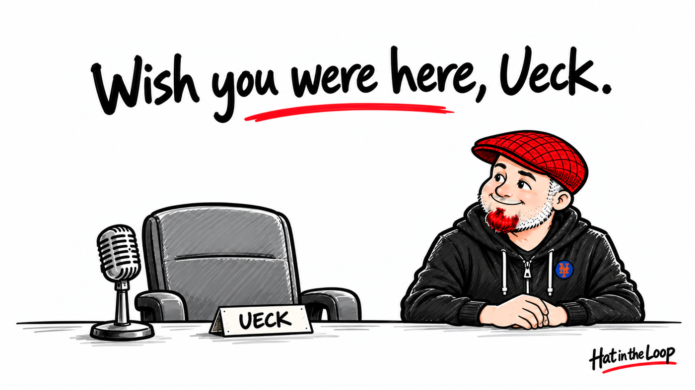 Minimal whiteboard tribute reading “Wish you were here, Ueck.” An empty announcer’s chair and microphone sit beside Aaron Murray in his red flat cap, with a small Mets pin.